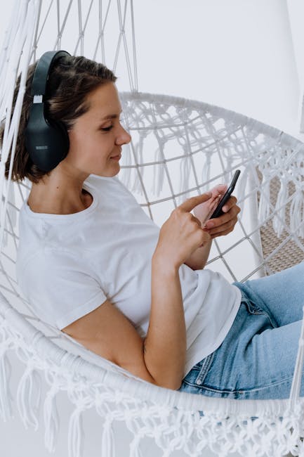 A woman relaxing in a hanging chair listening to high-quality music on a mobile device